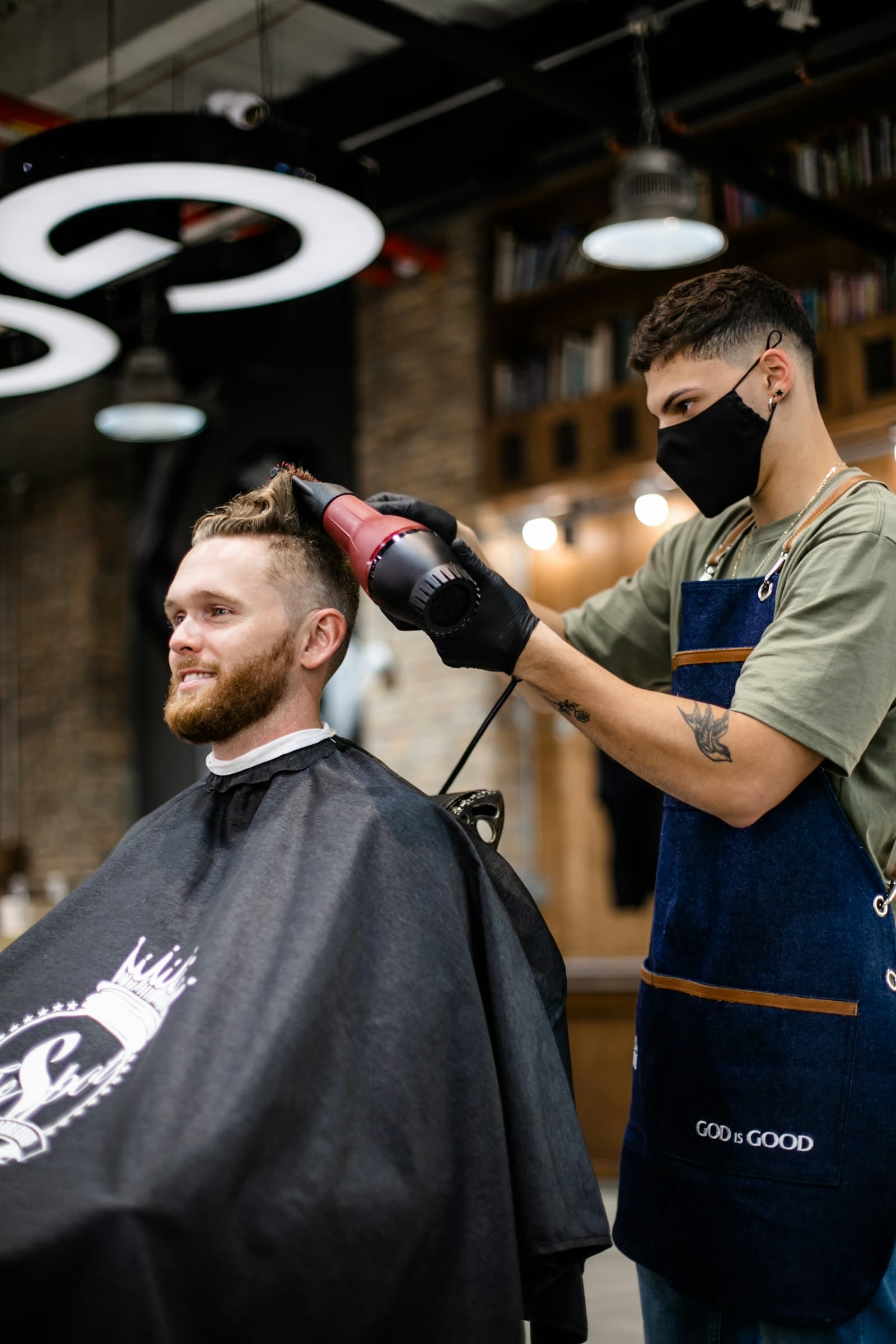 A barber finishing a client's haircut with a blow dryer
